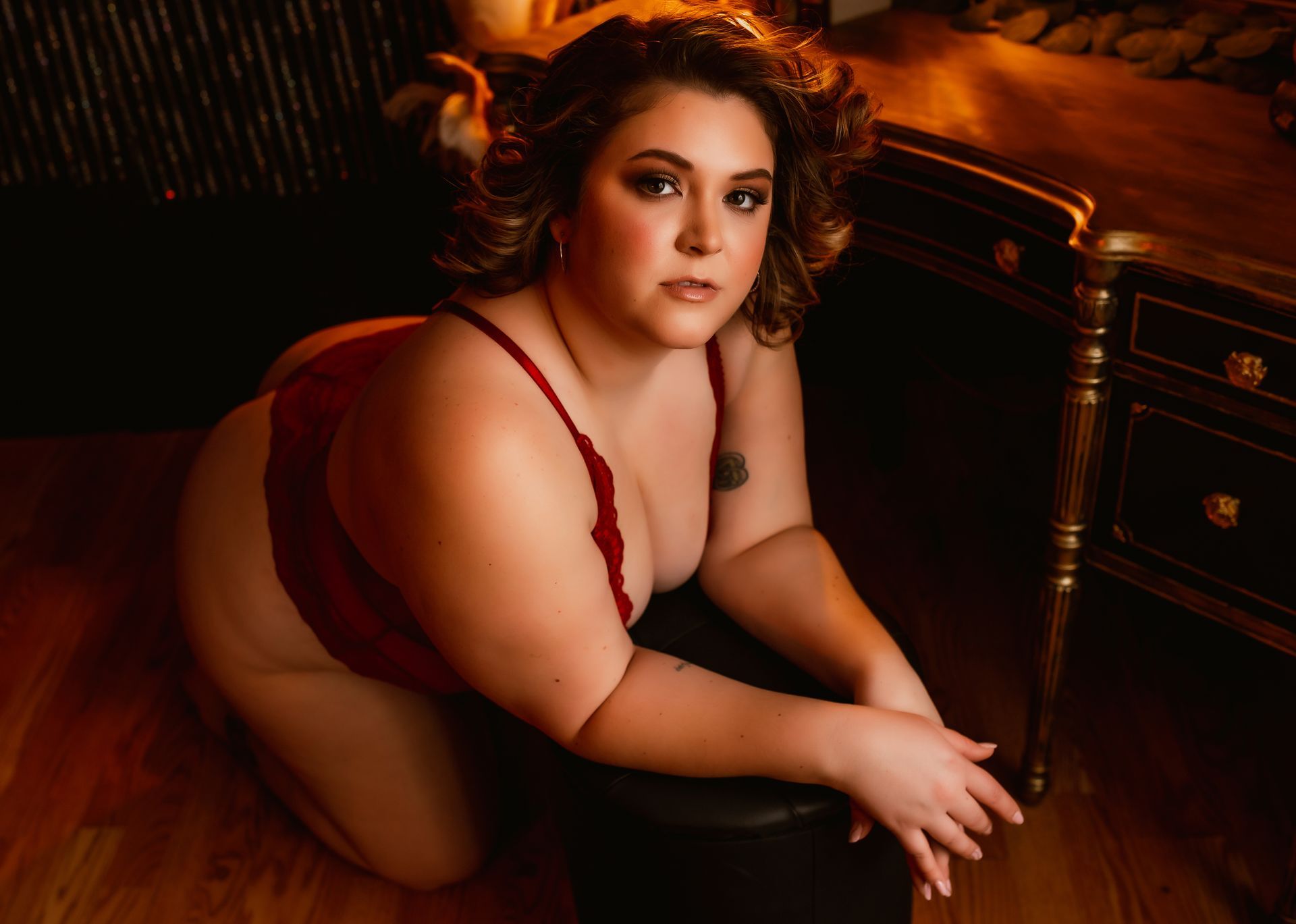 A woman in lingerie is kneeling on the floor in front of a desk.
