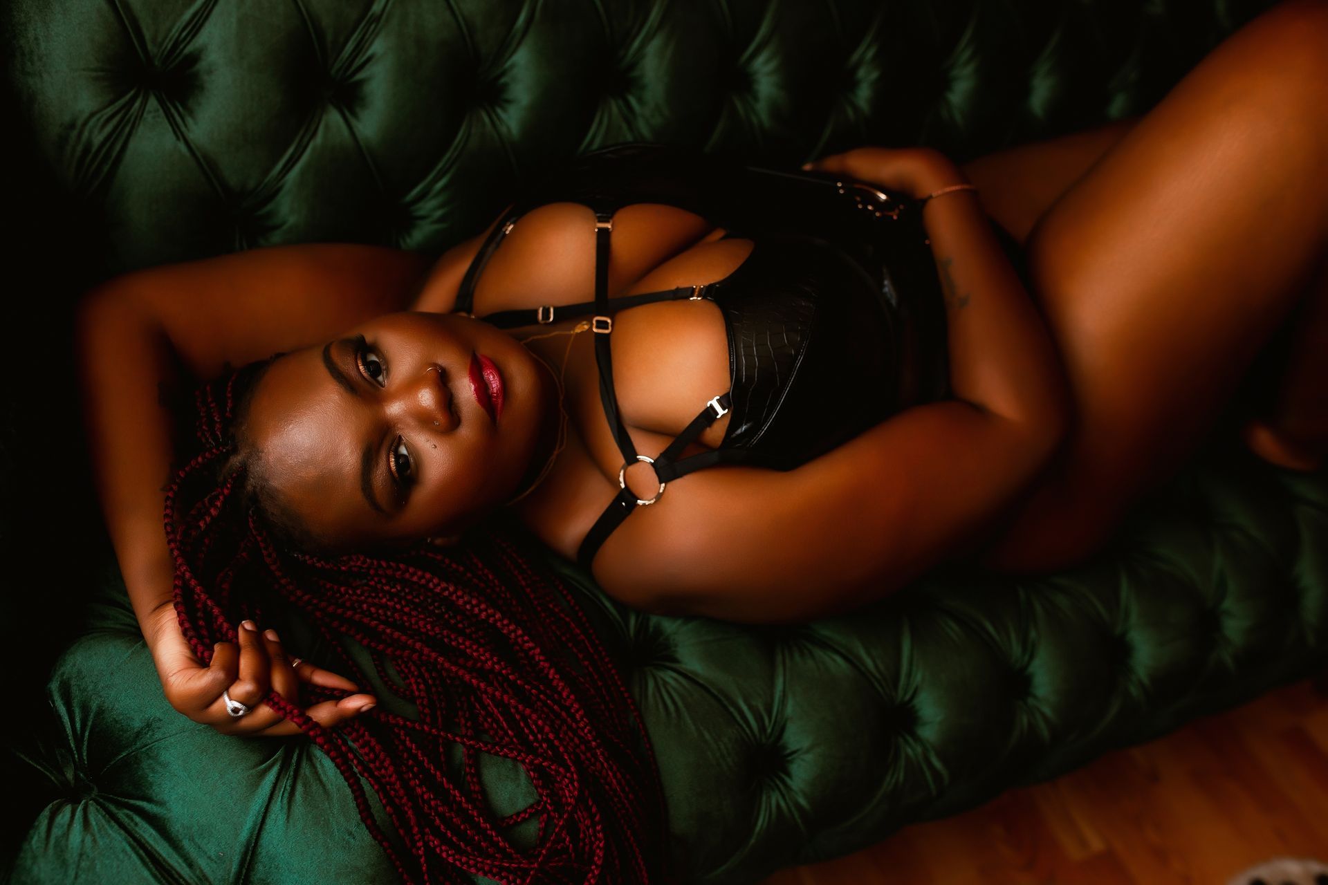 A woman in lingerie is laying on a green couch.