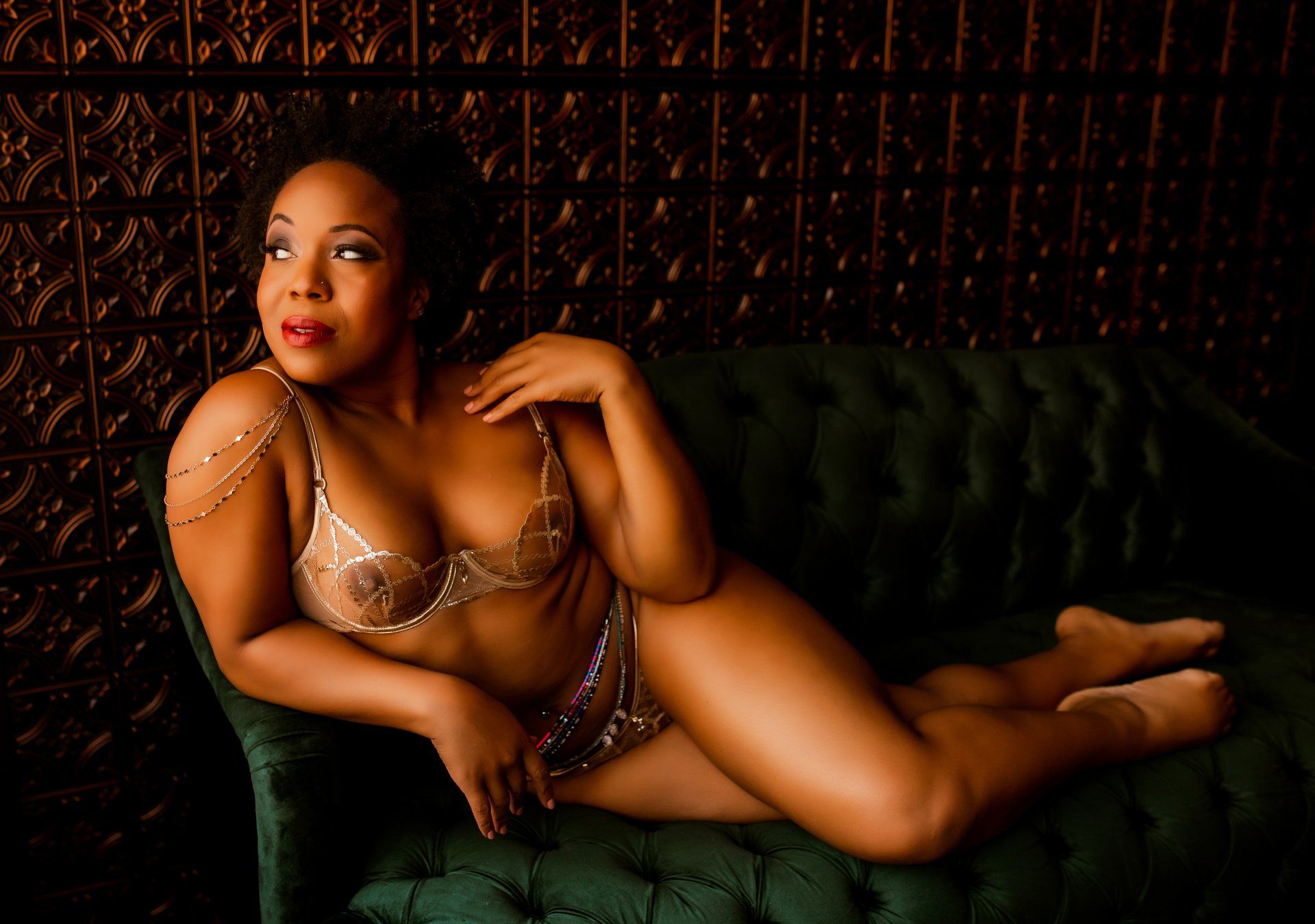 A woman in lingerie is laying on a green couch.
