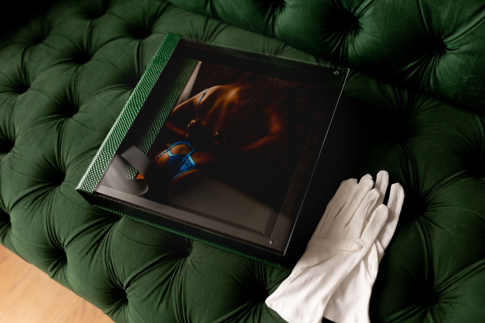A green couch with a picture of a woman on it and a pair of white gloves.