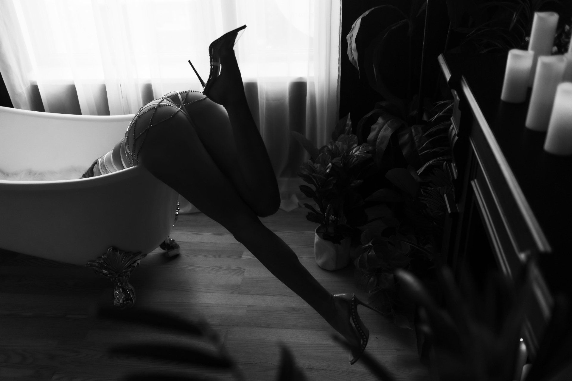 A black and white photo of a woman laying on the floor next to a bathtub.