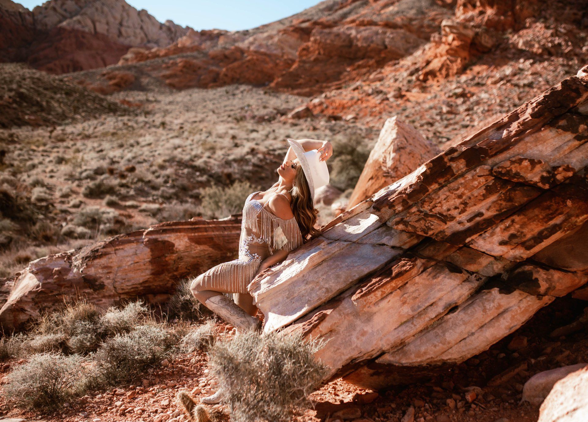 A woman is sitting on a rock in the desert.