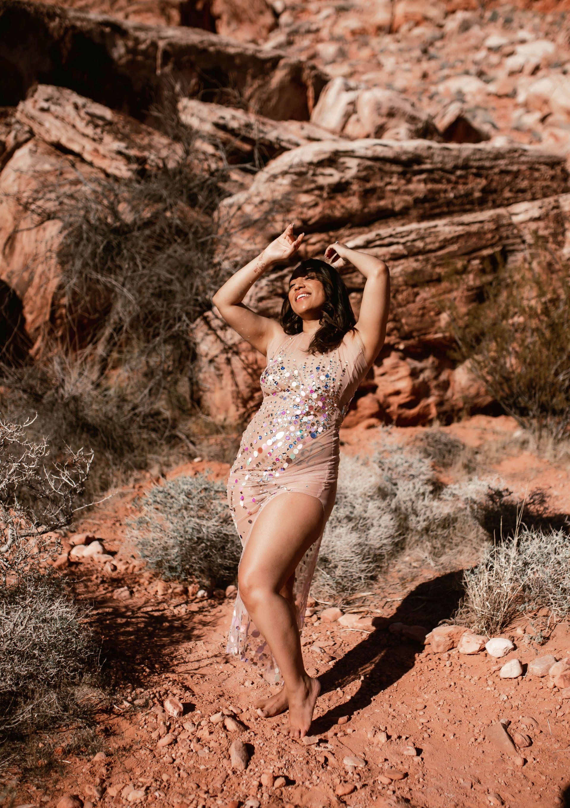 A woman in a dress is standing in the desert.
