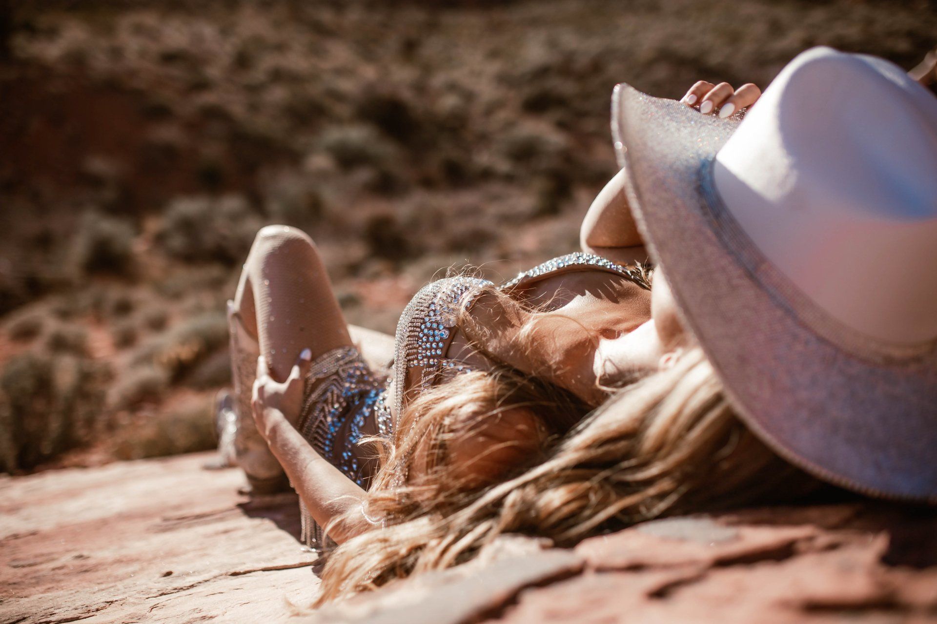 A woman in a white hat is laying on a rock.