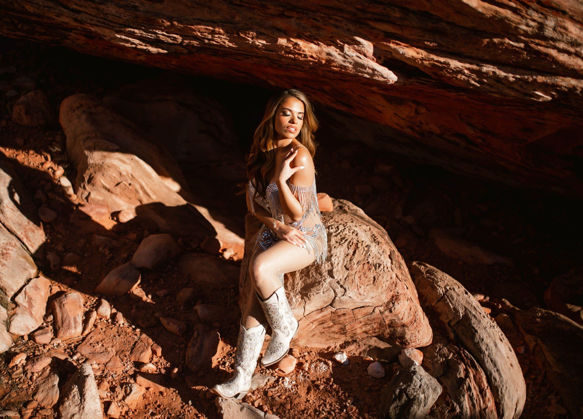 A woman is sitting on a rock in a cave.