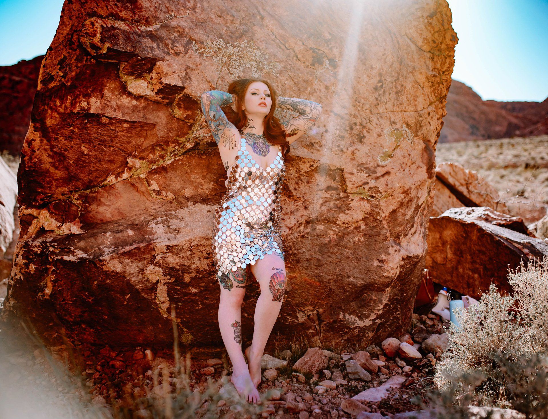 A woman in a dress is standing next to a large rock.