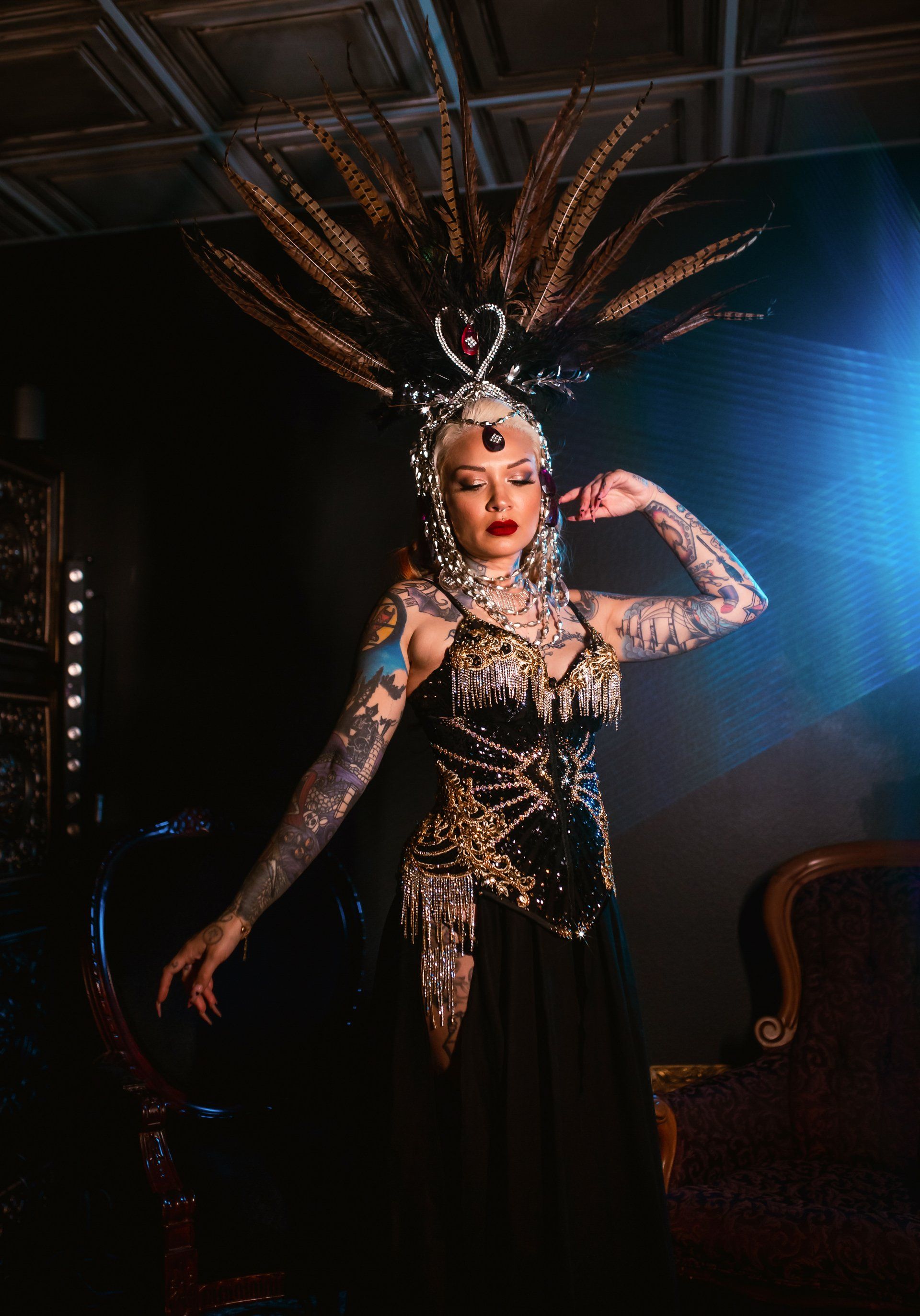 A woman in a costume with feathers on her head is standing in a dark room.