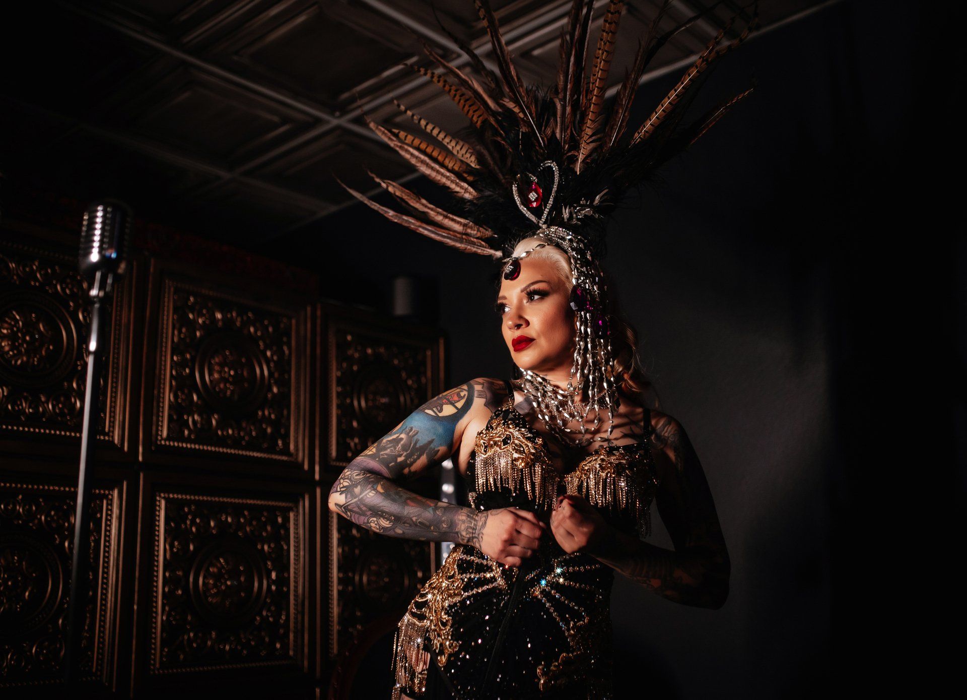 A woman in a costume with feathers on her head is standing in front of a microphone.
