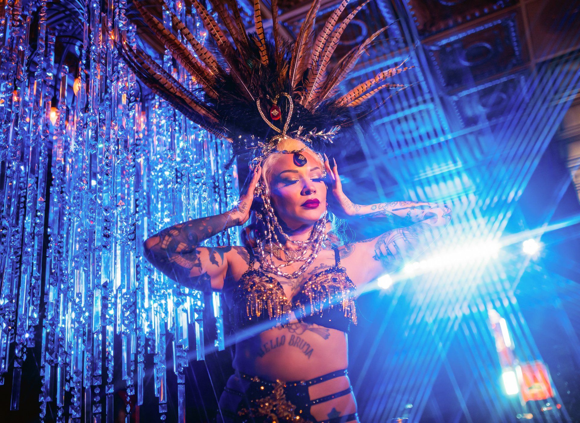 A woman in a carnival costume is standing in front of a blue curtain.