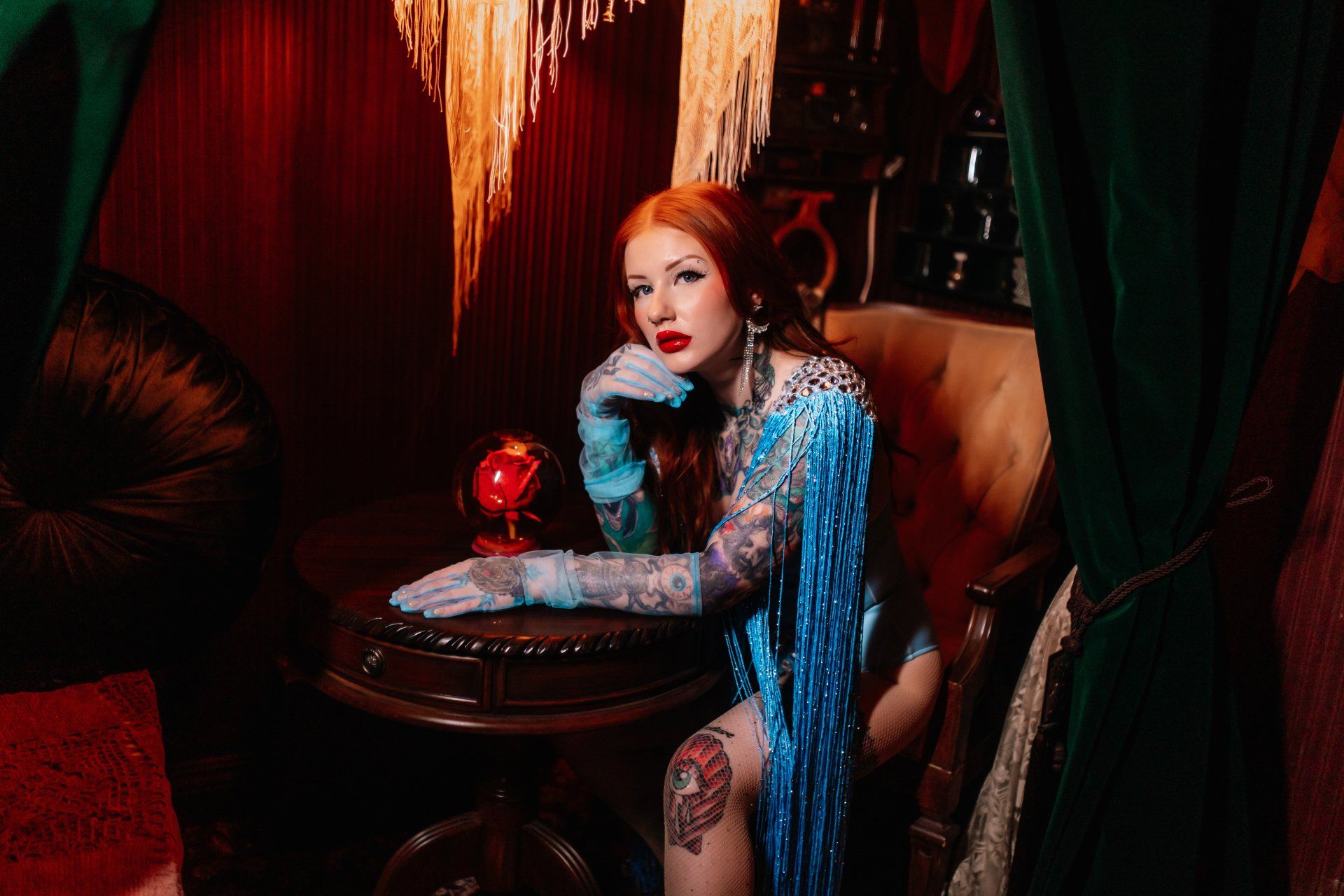 A woman in a blue dress and gloves is sitting in a chair.