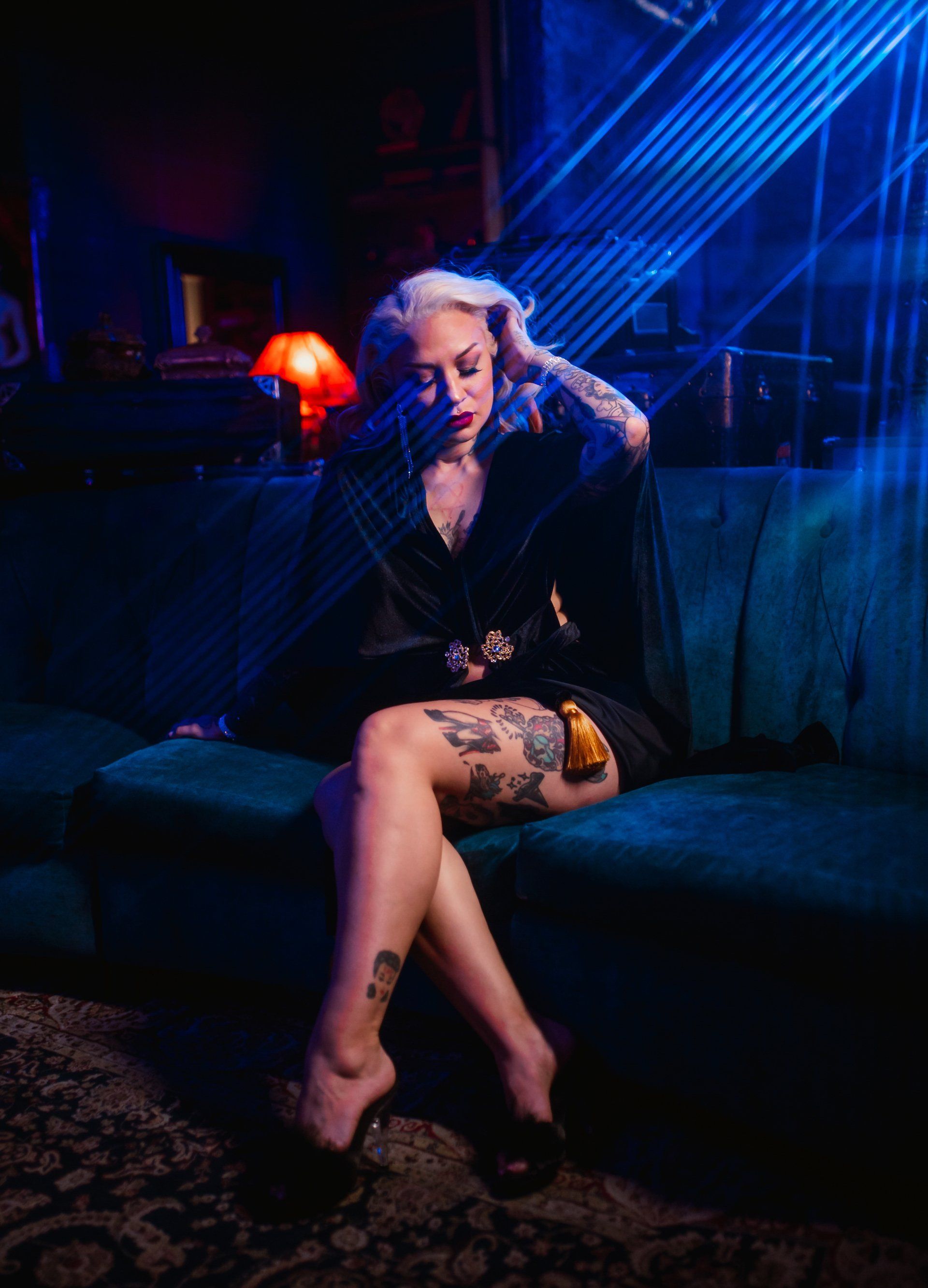 A woman is sitting on a couch with her legs crossed in a dark room.