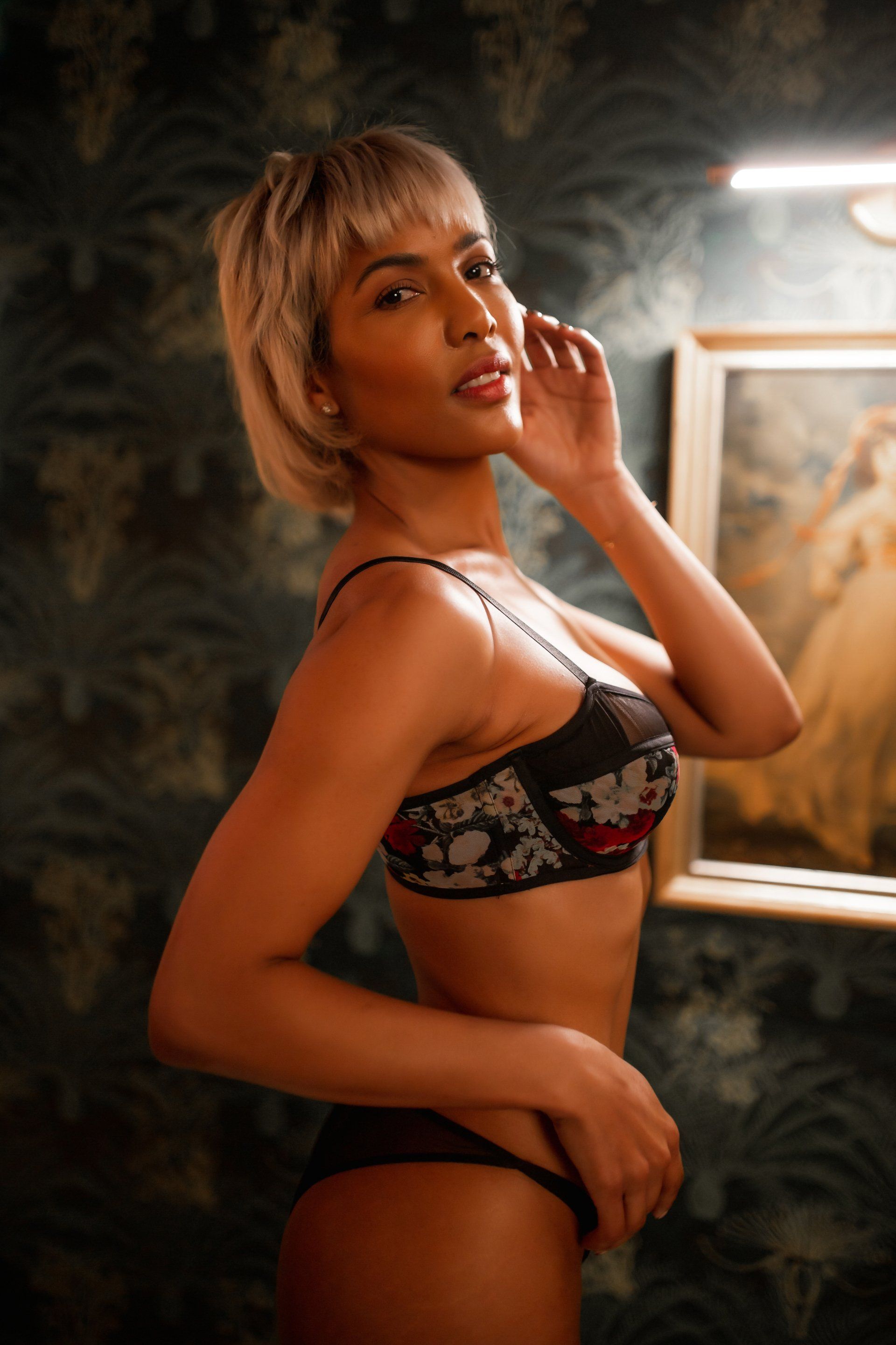 A woman in lingerie is standing in front of a painting.