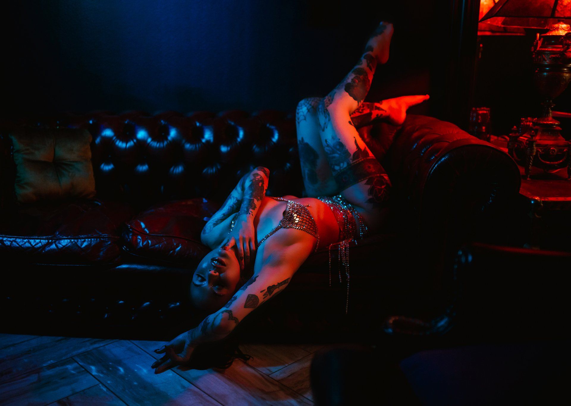 A woman is laying on her back on a couch in a dark room.
