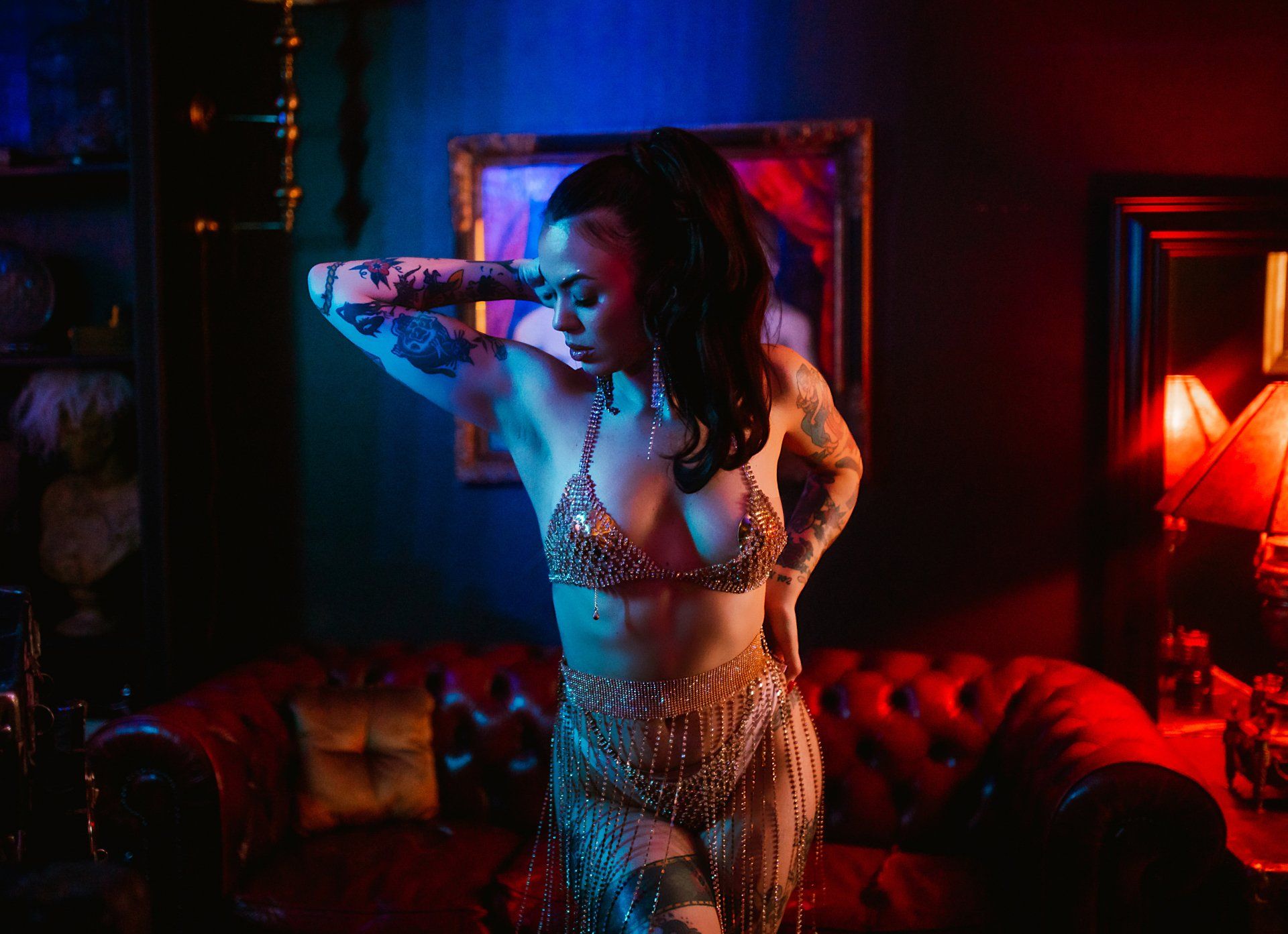 A woman in a bra and skirt is standing in a dark room.