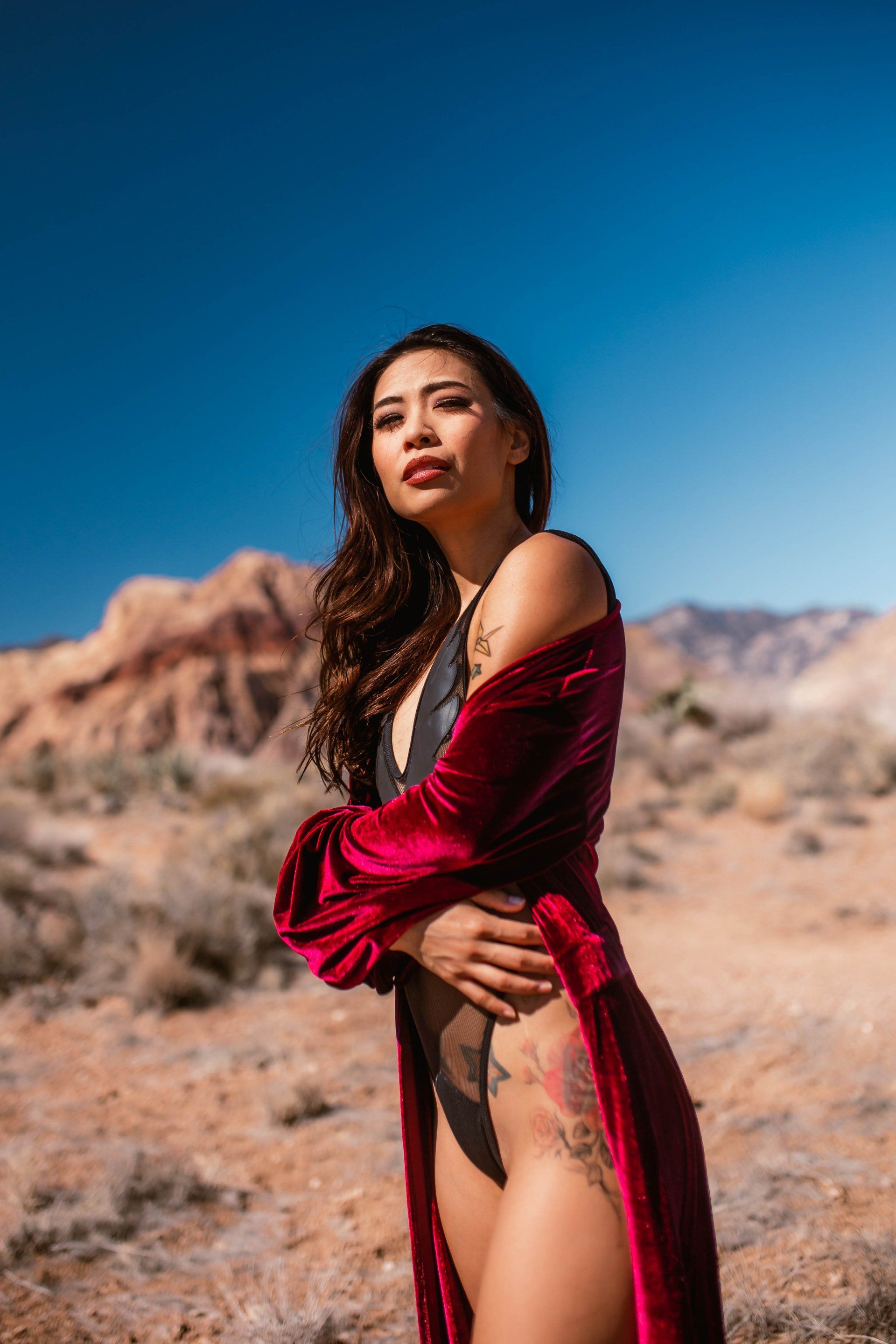 A woman in a red robe is standing in the desert.