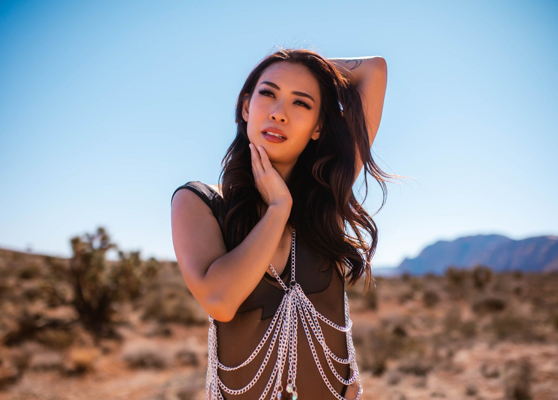 A woman is standing in the desert wearing a body chain.