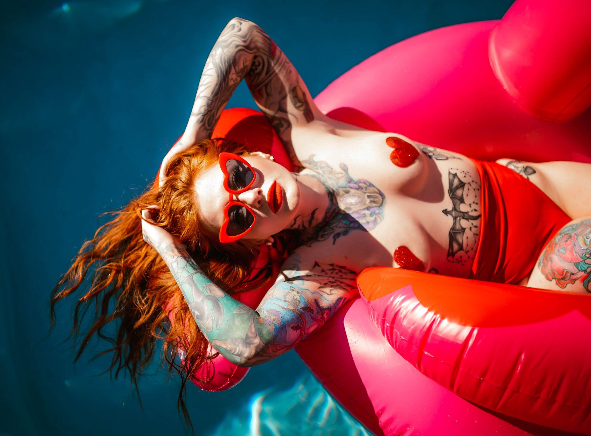 A woman is laying on a pink flamingo float in a pool.