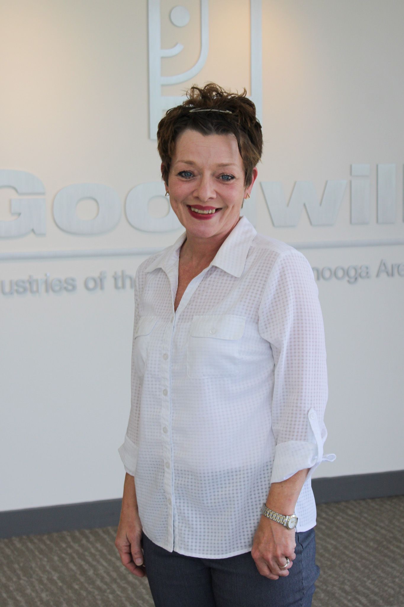 A woman in a white shirt is standing in front of a wall with the word rockwell on it.