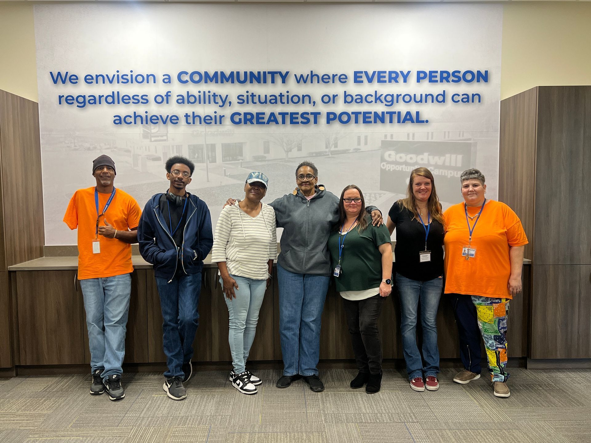 A group of people are posing for a picture in front of a wall with a quote on it.