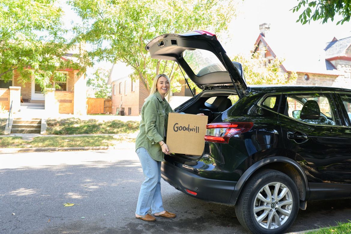 A woman is loading a box into the back of a car.