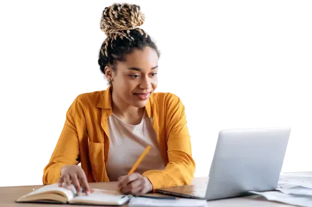 A woman is sitting at a desk with a laptop and a notebook.