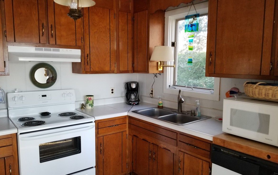 Kitchen with wood cabinets, white appliances, and a small window.