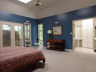 Bedroom with blue walls, carpet, bed, dresser, and open door to bathroom.