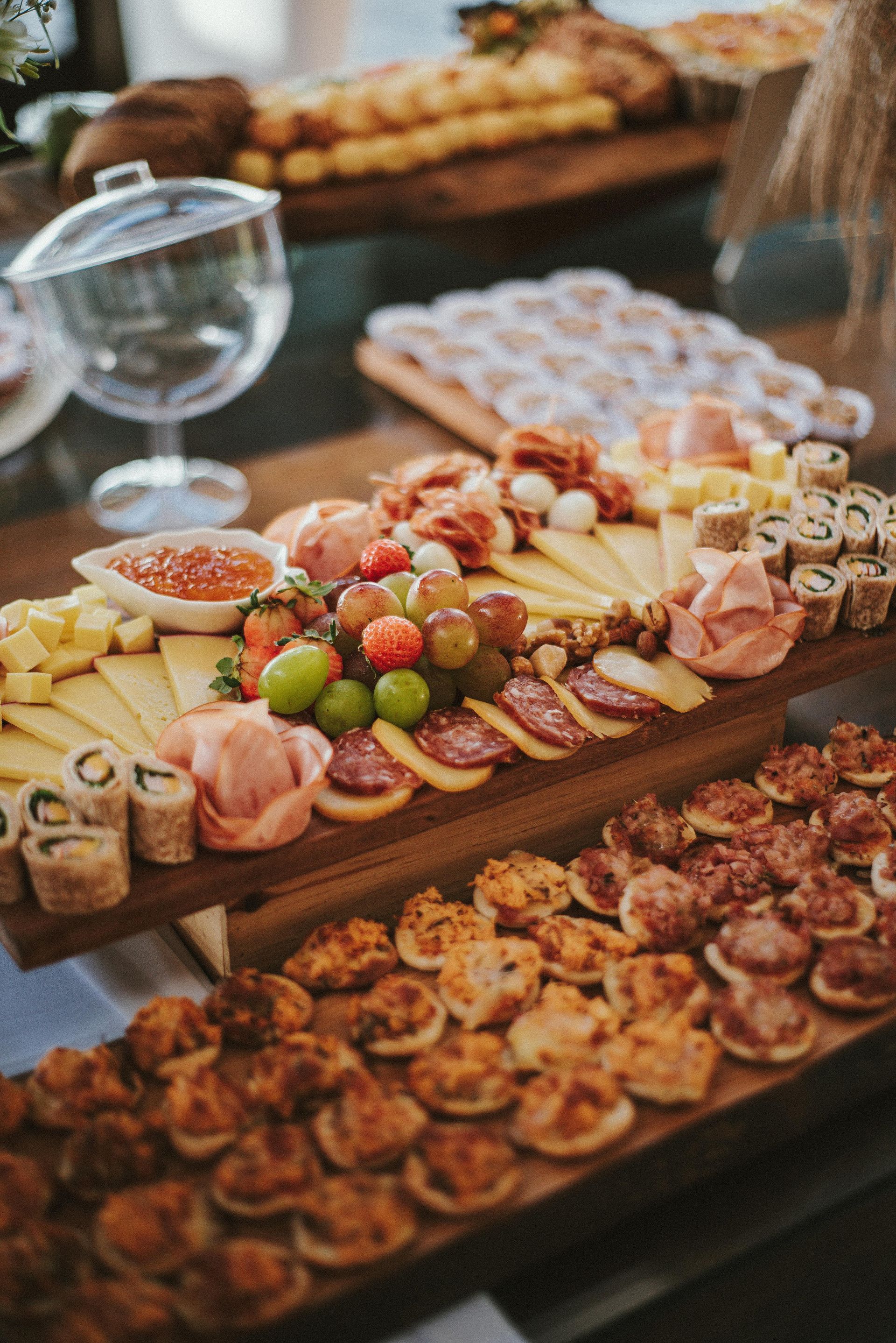 Charcuterie and appetizer platters with fruit, cheese, meats, and pastries on a wooden table at a buffet