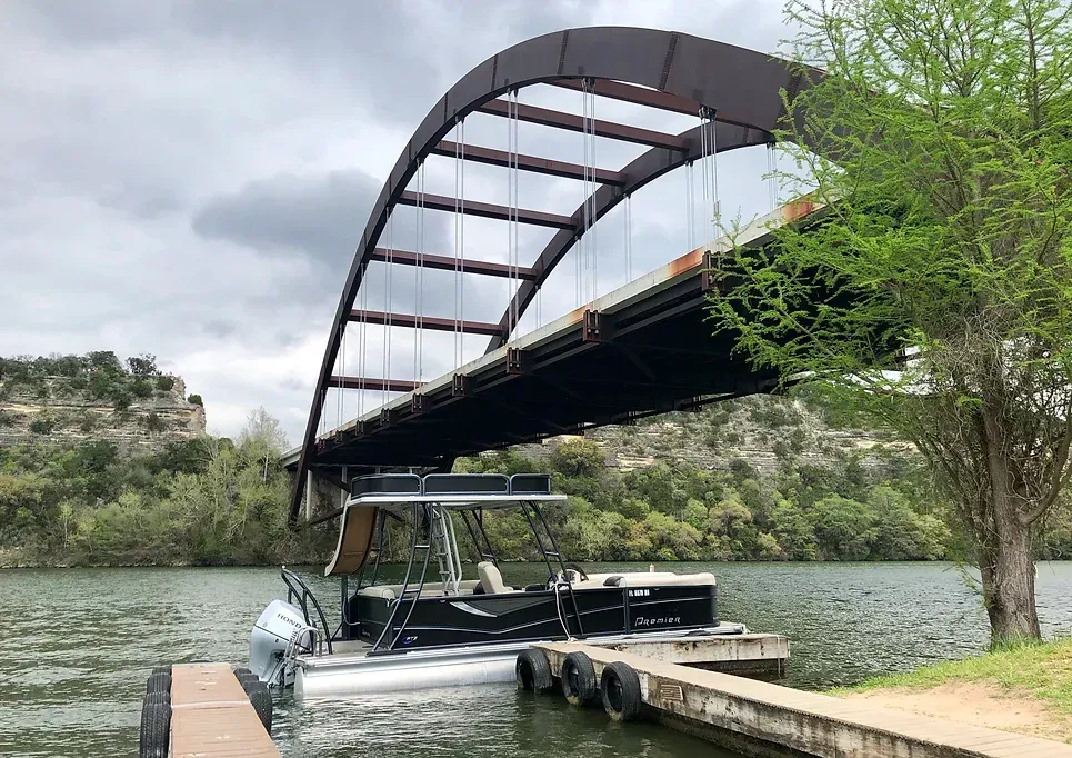 A boat is docked under a bridge over a lake.