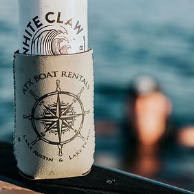 A can of white claw beer is sitting on a dock next to the water.