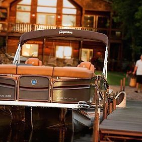 A pontoon boat is docked at a dock in front of a house.
