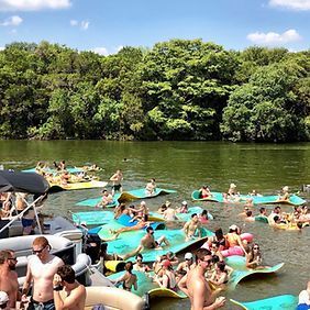 A large group of people are floating on rafts in a lake.