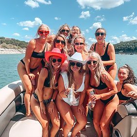 A group of women in bikinis are posing for a picture on a boat.