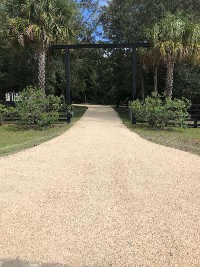 Stone path flanked by concrete walls, gravel, and green bushes.