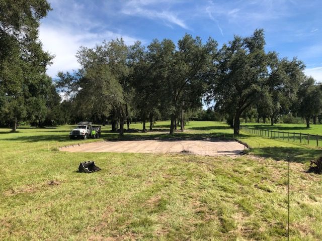 Grassy park with a dirt path, trees, and a picnic table under a blue sky