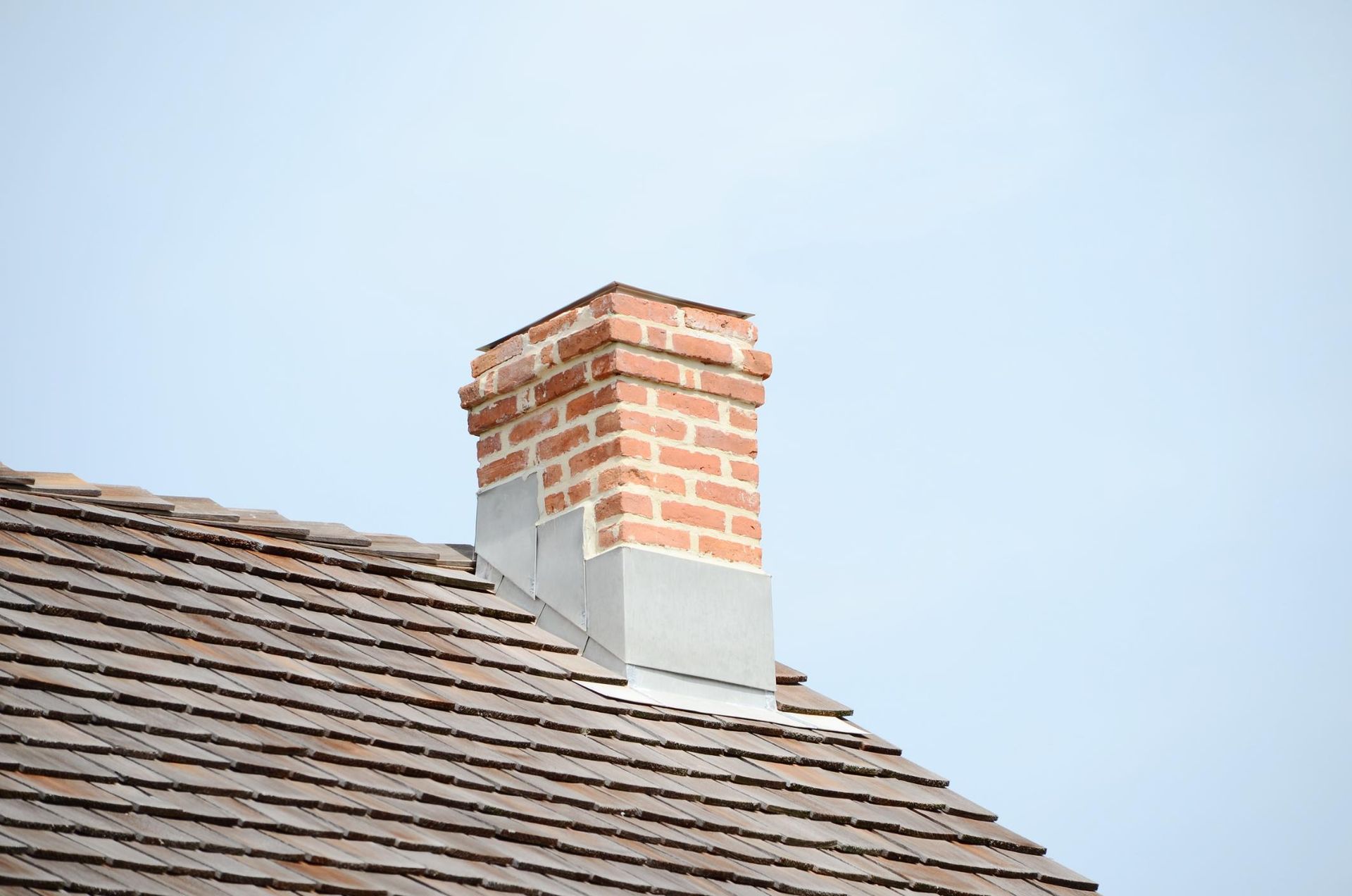A brick chimney is on the roof of a house.