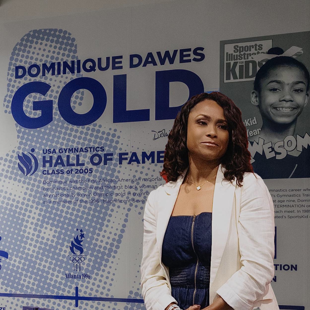 Dominique Dawes posing in front of a gold Hall of Fame backdrop at a sports event.