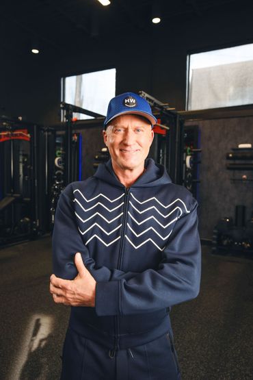 Eric North wearing a blue Happiness Warrior hat and jacket with strips on the front