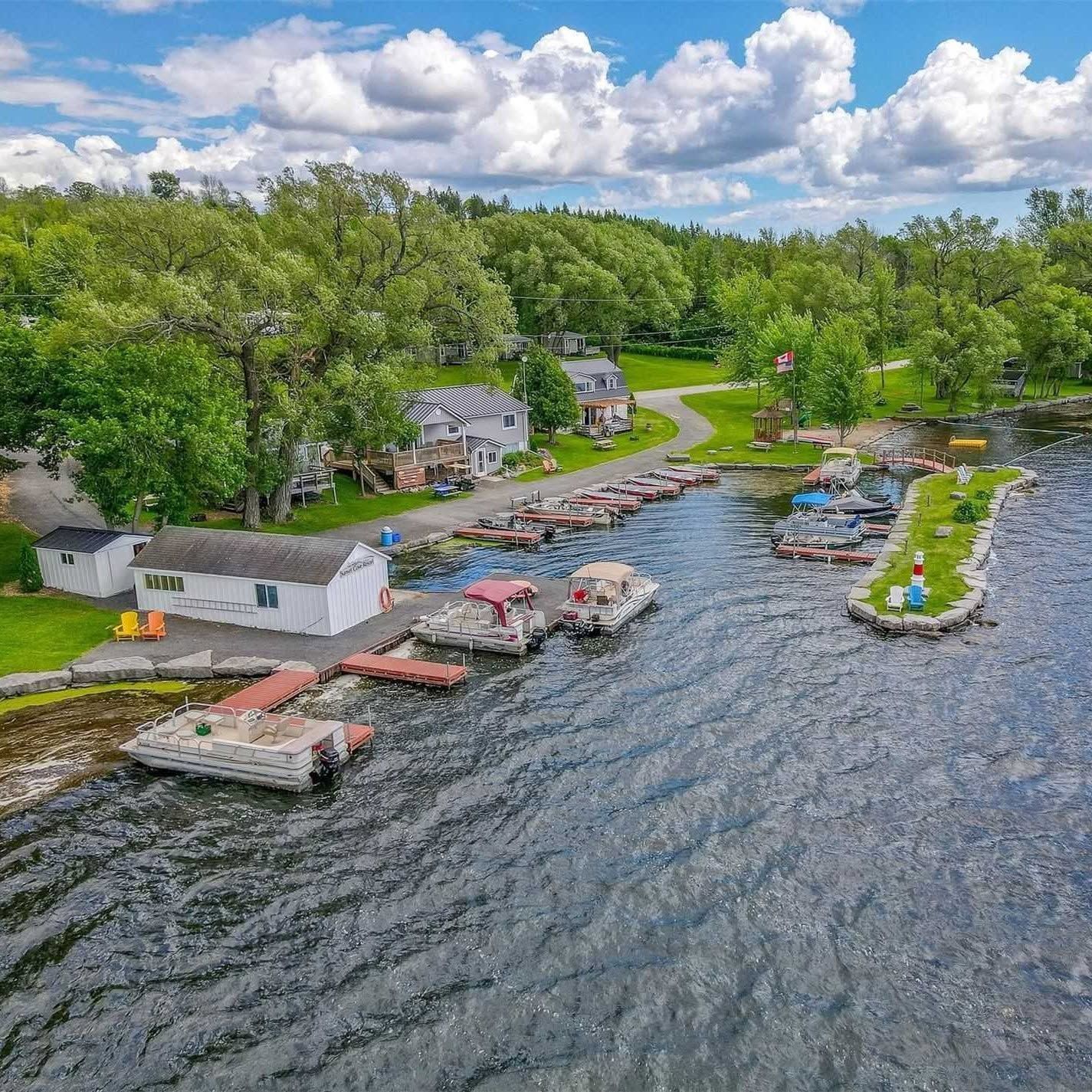 Aerial view of lakeside cabins and docks along a wooded shoreline under a cloudy blue sky