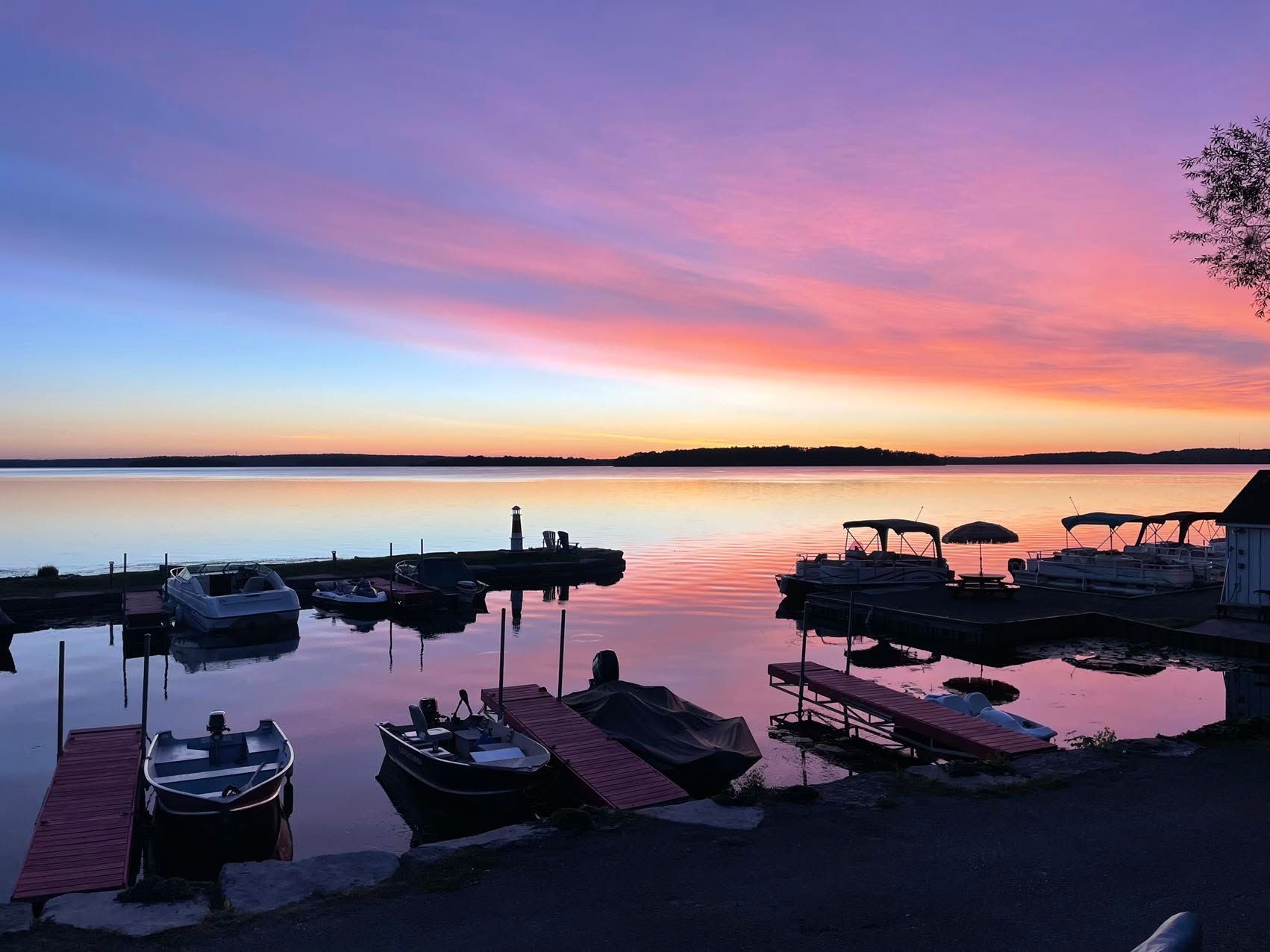 Sunset over a calm marina with docked boats silhouetted against pink and purple sky