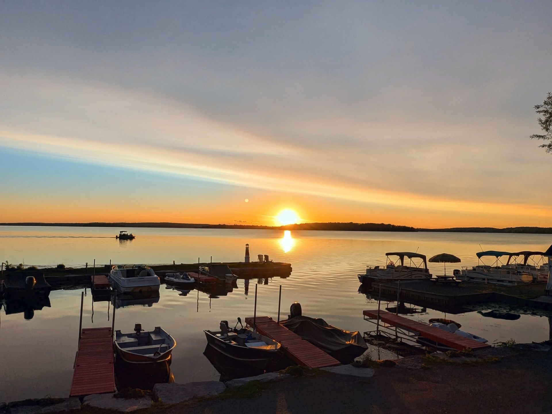 Sunset over a calm lake with docked boats and a colorful sky