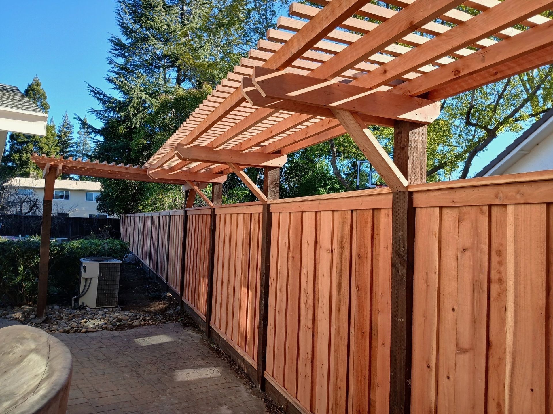 Wooden fence with attached pergola in a backyard.