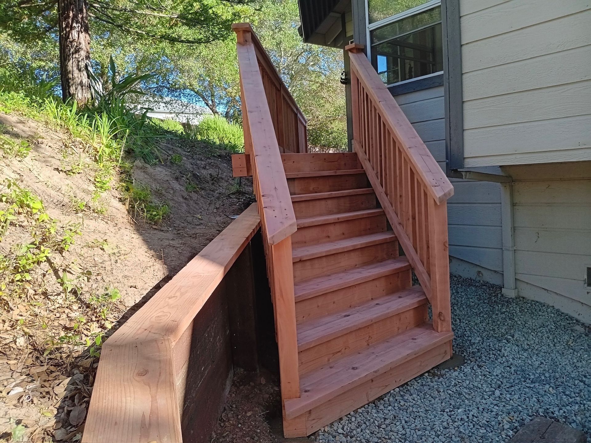 Wooden outdoor staircase leading up a hillside to a building entrance.