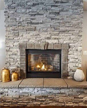 Stone fireplace with a lit fire, gold canisters, and a white vase.
