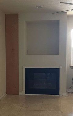 Fireplace with a recessed shelf above it and a wooden panel to the left.