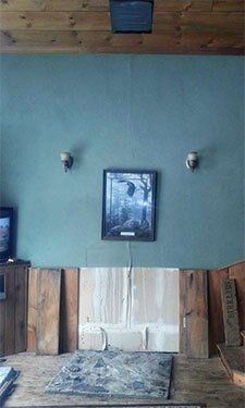 A room with a teal wall, wooden paneling, and a framed artwork in the center.