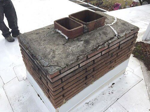 Wood-burning stove inside brick fireplace with black stove pipe, a brick surround, and hearth.
