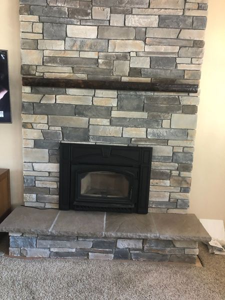 Stone fireplace with black fireplace insert and dark wood mantel.