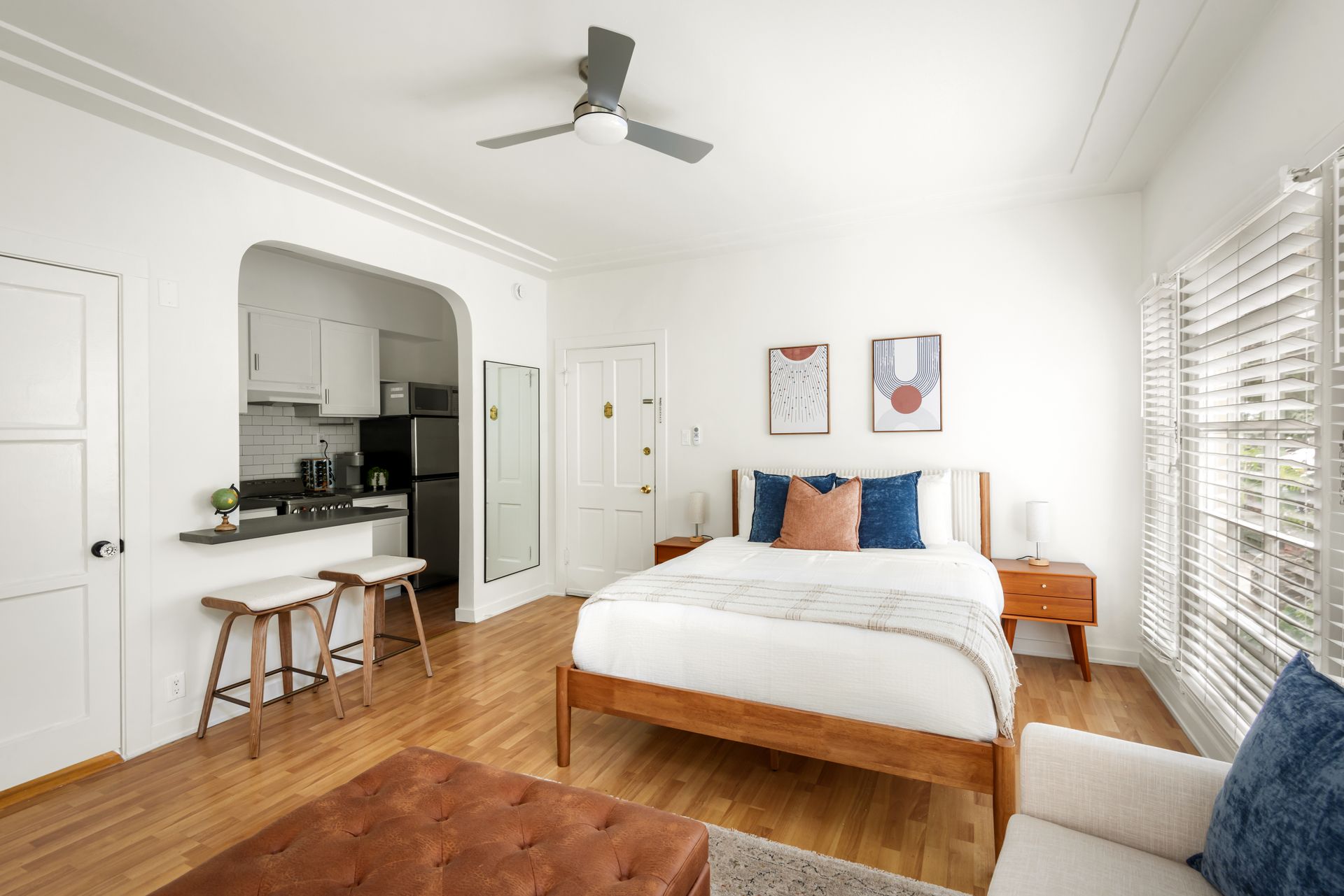 Cozy studio apartment with a bed, kitchenette, and wooden floors.