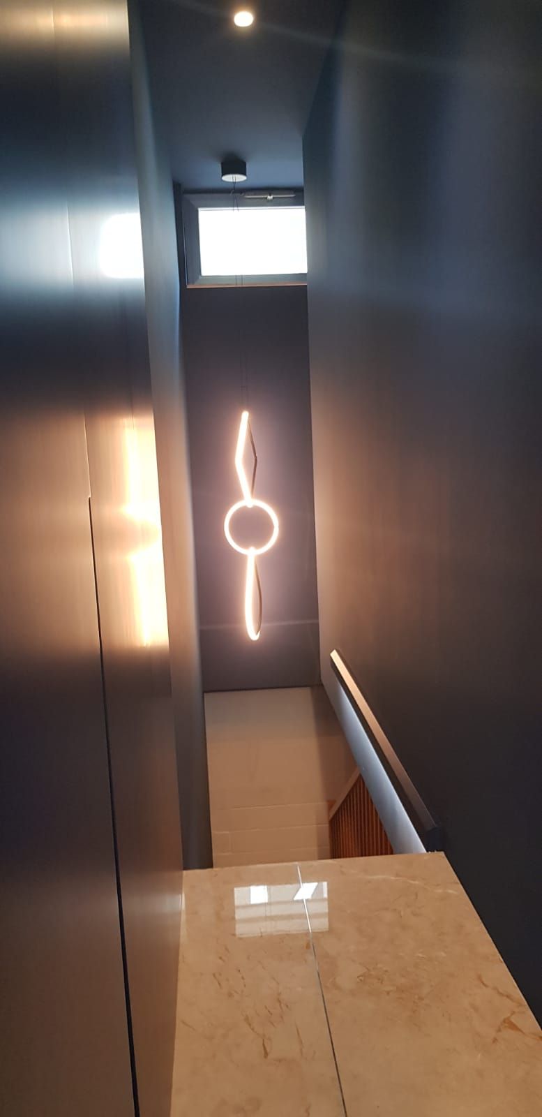 Corridoio stretto con scale. Un'insegna al neon è montata sul muro.
